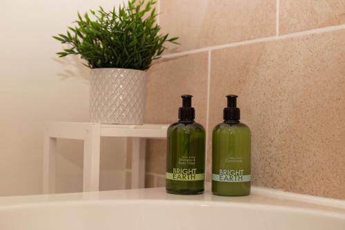 two green glass bottles sitting on a bathroom sink at Painters Modern Apartment Central Location in Scarborough