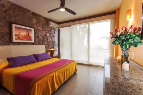 a bedroom with a bed and a vase of flowers at Vallarta Shores Beach Hotel in Puerto Vallarta