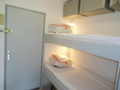 Ce dortoir comprend 2 lits superposés et une porte. dans l'établissement Joli studio cabine Vue Mer dans une Résidence avec Piscine, à Cavalaire-sur-Mer