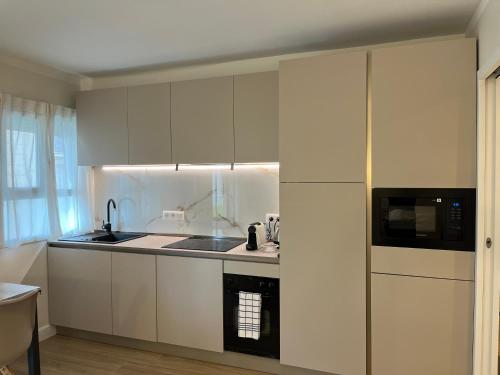 a kitchen with white cabinets and a black microwave at Appartements 5MIN MONTE CARLO in Beausoleil