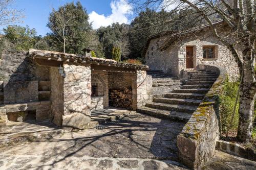 an old stone building with stairs and a door at Molí d'en Puig in Vall de Bianya