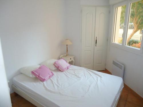 une chambre avec un lit avec des oreillers roses dessus dans l'établissement Appartement 3 Chambres PISCINE 500M PLAGE, à Cavalaire-sur-Mer
