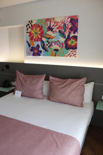 a bed with pink pillows and a painting above it at Mercure Rosario in Rosario
