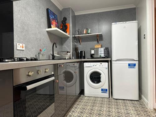 a kitchen with a washing machine and a refrigerator at Private Main Door Lovely 2 bedroom apartment in Edinburgh