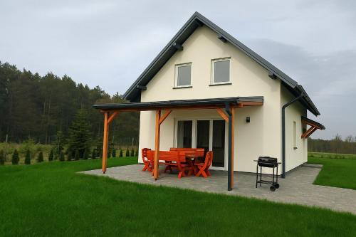 a house with a table and chairs on a patio at Domek letniskowy nad morzem in Osieki Leborskie