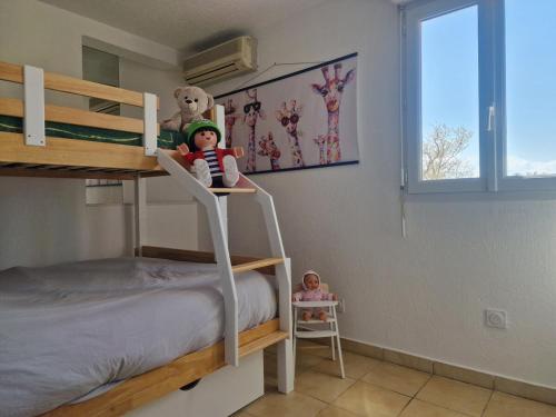 - une chambre avec des lits superposés et une poupée sur une échelle dans l'établissement Cocon canetois, à Canet