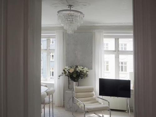 a living room with a chandelier and a chair and a television at Artsy & Bright - Scandinavian Apartment in Copenhagen
