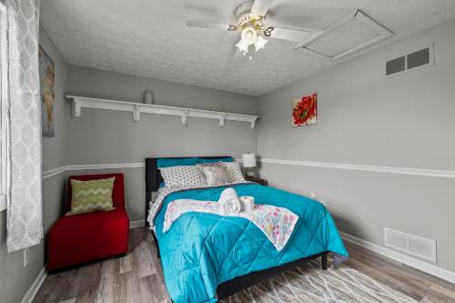 a bedroom with a blue bed and a red chair at Cosy house, home away from home in Grove City