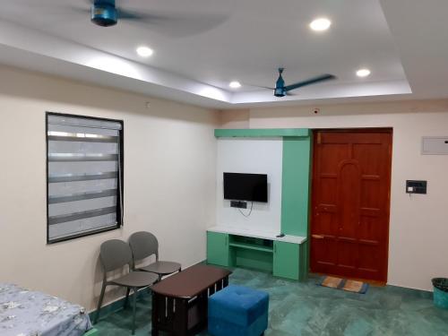 a room with a table and chairs and a television at Swagan Home Stays Air Conditioned Deluxe ONE BED ROOM Studio Apartment in Visakhapatnam
