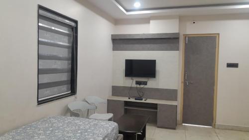 a bedroom with a bed and a tv on the wall at Swagan Home Stays Air Conditioned Deluxe ONE BED ROOM Studio Apartment in Visakhapatnam