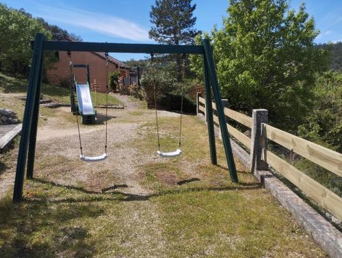 a swing set in a yard with a fence at Maison de vacances dans les hauteurs de Salavas in Salavas