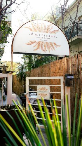 a sign for a restaurant with a fence at Americana Beach House in Rimini