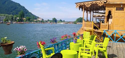 een groep gele stoelen en tafels op een steiger naast een meer bij Jacqueline houseboat in Srinagar