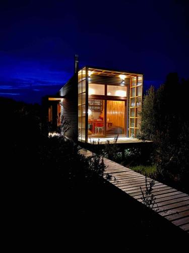 a house with a lit up facade at night at Tinyhouse Pichi I - vida lenta en Patagonia Costa in Calbuco