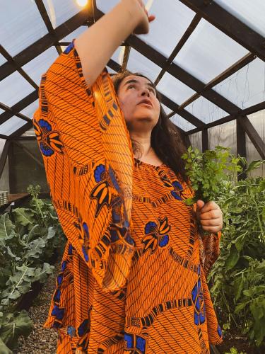 a woman standing in a greenhouse holding a plant at Tinyhouse Pichi I - vida lenta en Patagonia Costa in Calbuco