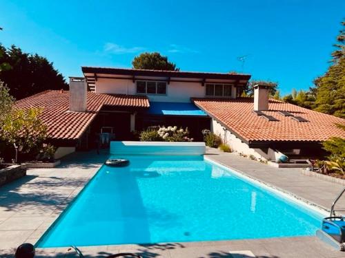 une grande piscine devant une maison dans l'établissement Villa Entre lac, forêt, océan, à Biscarrosse