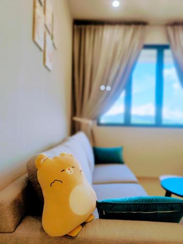 a stuffed animal sitting on a couch in a room at Iconic Regency Service Residences - Xin's Home in Bayan Lepas
