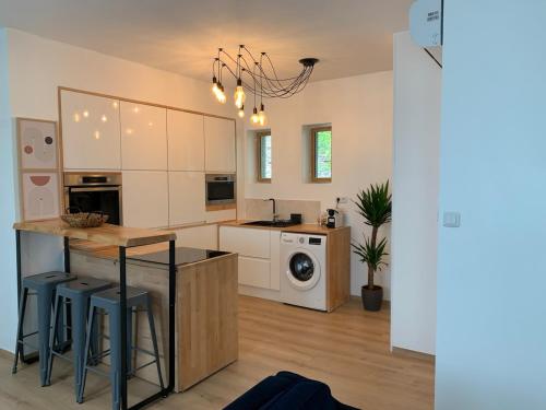 une cuisine avec des armoires blanches et un îlot de cuisine avec des tabourets dans l'établissement Appt Place Gramont, à Pau