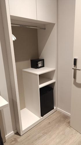 a small closet with white shelves and a clock on it at Hotel Acquario in Genova