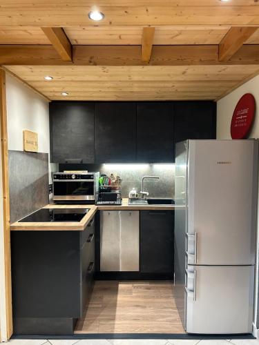 une cuisine avec des armoires noires et un réfrigérateur en acier inoxydable dans l'établissement Manigod, en route pour les vacances !, à Manigod