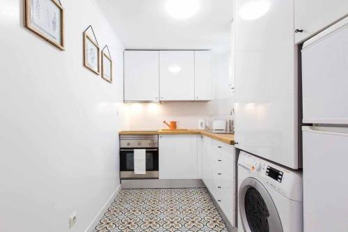 a kitchen with white cabinets and a washer and dryer at Gem of Alfama in Lisbon