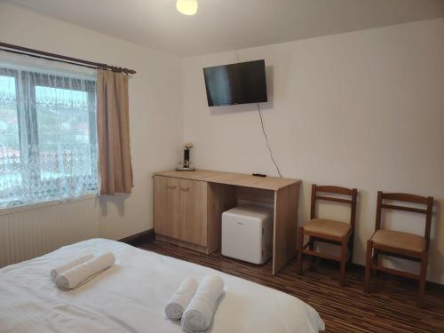 a bedroom with a bed and a tv and two chairs at Casa MonyBeea in Silvaşu de Sus