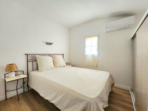 une chambre blanche avec un lit et une fenêtre dans l'établissement Jasses de Camargue, à Gallargues-le-Montueux