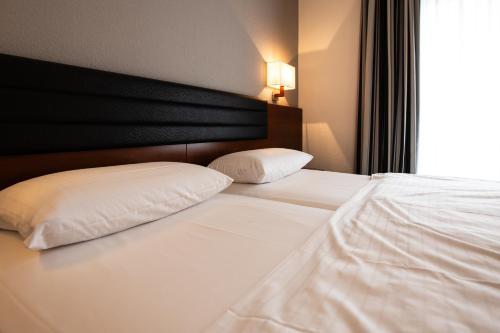 a bedroom with two white pillows on a bed at Ringhotel Appelbaum Gütersloh in Gütersloh