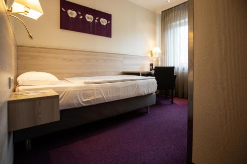 a hotel room with a bed and a desk at Ringhotel Appelbaum Gütersloh in Gütersloh