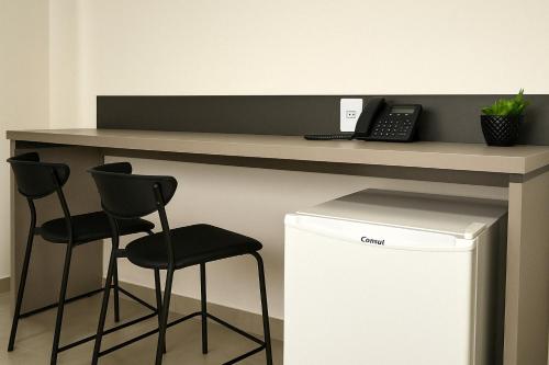 un bureau avec deux tabourets de bar et un téléphone dans l'établissement Suíte Privilegiada no Centro - Golden Dolphin, à Caldas Novas