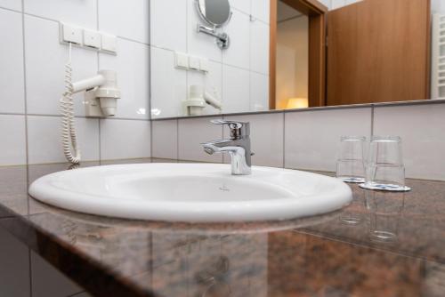 a bathroom sink with two glasses and a mirror at Ringhotel Appelbaum Gütersloh in Gütersloh