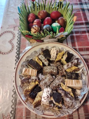 a plate of desserts on a table with a bowl of apples at Casa MonyBeea in Silvaşu de Sus