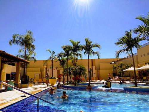 a group of people in a swimming pool with palm trees at Thermas Boulevard Suíte Hotel - Weigly in Caldas Novas