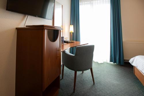 a hotel room with a desk and a chair at Ringhotel Appelbaum Gütersloh in Gütersloh