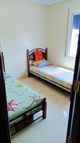 a bedroom with two beds and a window at Appartement meublé en centre ville in Souani
