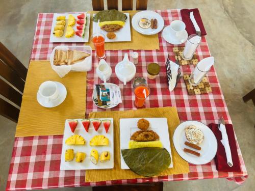 a table with plates of food on a red and white table cloth at Maapagala Resort Sigiriya in Sigiriya