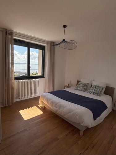 a bedroom with a large bed and a large window at maison vue mer avec terrasse in Brest