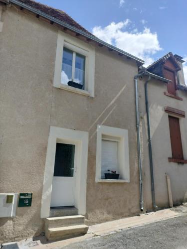 a house with two windows and a white door at La petite maison de poncho in Le Blanc