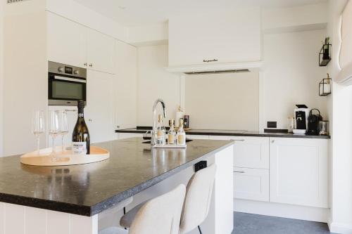 a kitchen with white cabinets and a counter with wine glasses at Casa La Vista - Puur onthaasten met wijds polderzicht in Blankenberge