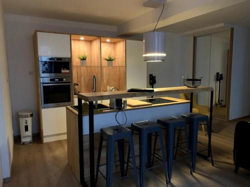 une cuisine avec tabourets bleus et comptoir avec évier dans l'établissement Appt Place Gramont, à Pau