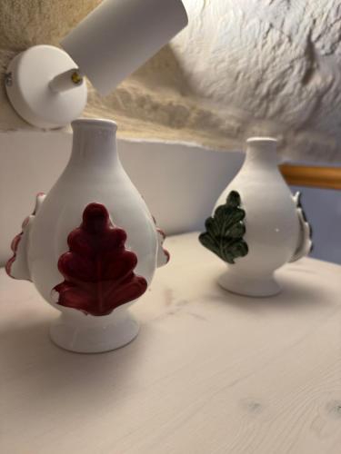 two white vases with a red flower on them at A Casa del Console apartment in Manfredonia