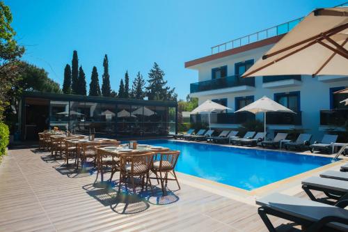 a swimming pool with tables and chairs next to a building at Çınar Butik Hotel Bodrum in Bodrum City