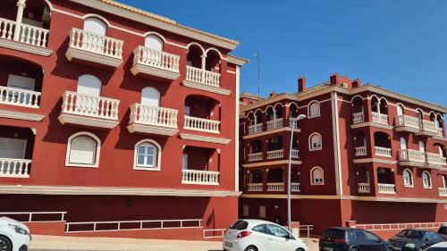 a red building with cars parked in front of it at APARTAMENTO DE AMY CON VISTA AL MAR 2 in Huelva