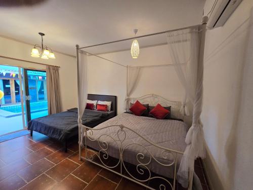 a bedroom with a canopy bed with red pillows at ForestPoolvilla in Na Jomtien