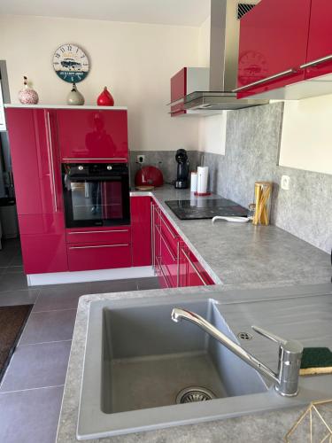 une cuisine avec des armoires rouges et un évier dans l'établissement Maison à la campagne, à Acy