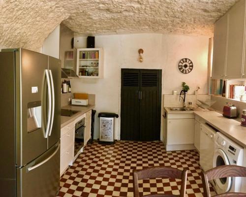 La cuisine est équipée d'un réfrigérateur noir et d'un sol en damier. dans l'établissement Charming troglodyte near Amboise, à Pocé-sur-Cisse