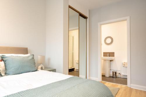 a white bedroom with a bed and a mirror at Grovefield Getaway in Belfast