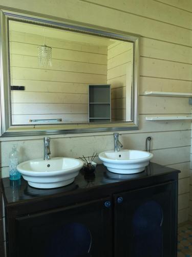 une salle de bain avec deux lavabos et un grand miroir dans l'établissement Maison en bois atypique, à Audenge