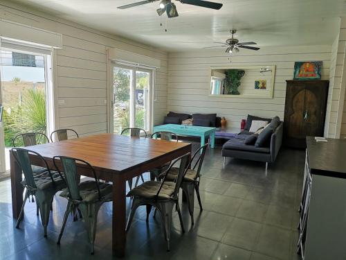 une salle à manger avec une table, des chaises et un canapé dans l'établissement Maison en bois atypique, à Audenge