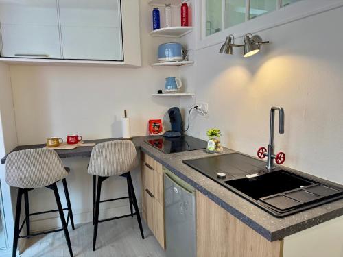 - une petite cuisine avec un évier et deux tabourets de bar dans l'établissement Studio cosy Paris 15, à Paris